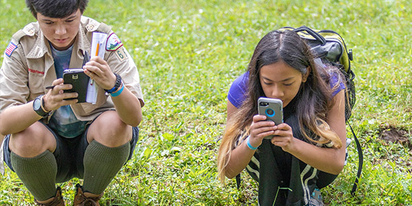 Two students outdoors, engrossed in photographing and examining various plant species for their study Two students outdoors, engrossed in photographing and examining various plant species for their study